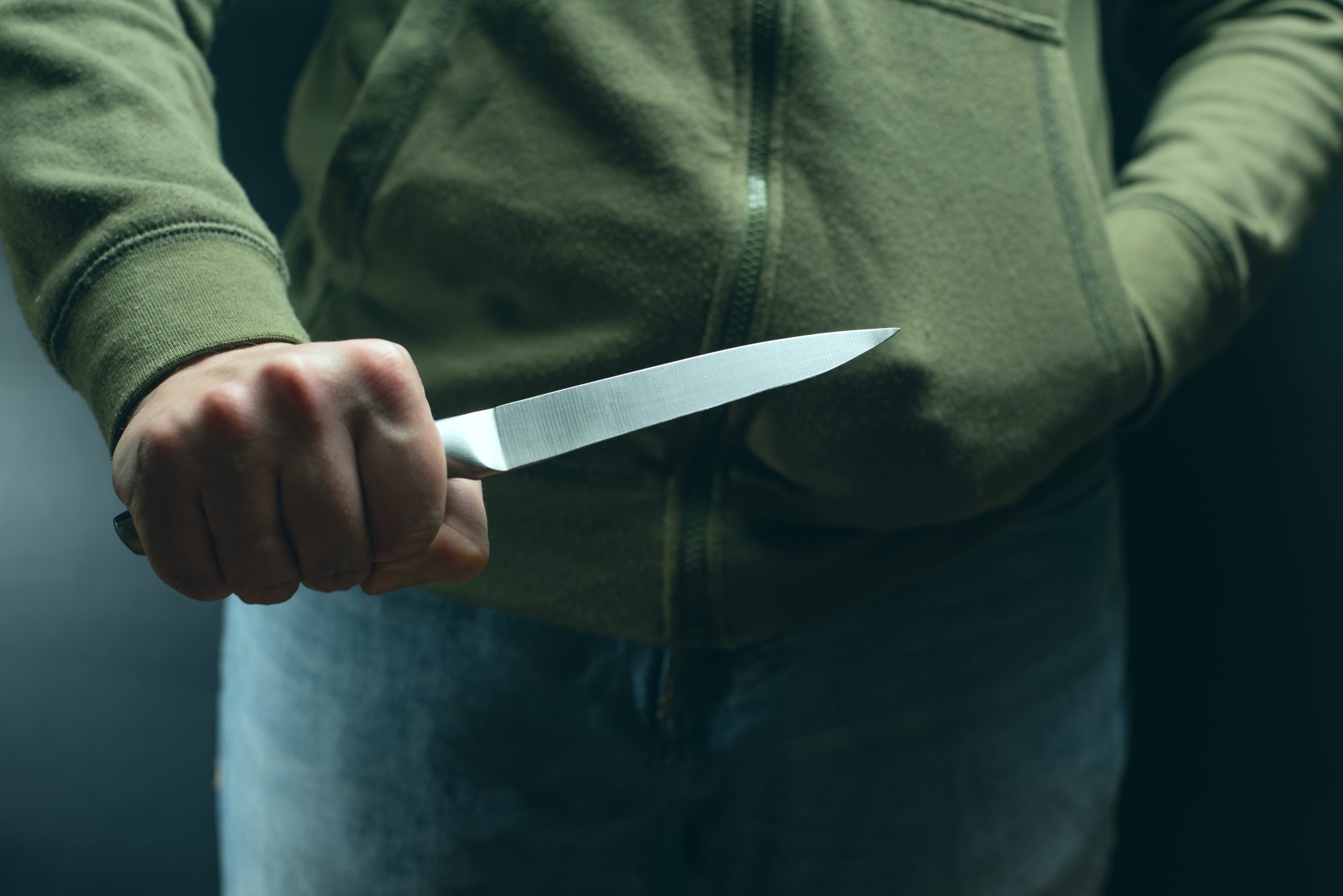 Человек угрожает ножом. Человек замахивается ножом.