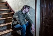 Man sat on staircase, tired and sad after drug relapse