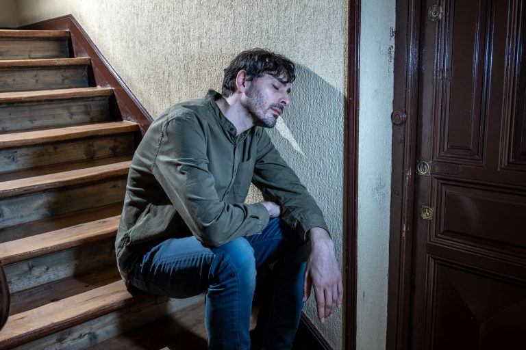 Man sat on staircase, tired and sad after drug relapse