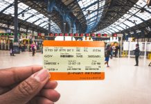 hand holding a train ticket in a station in the UK