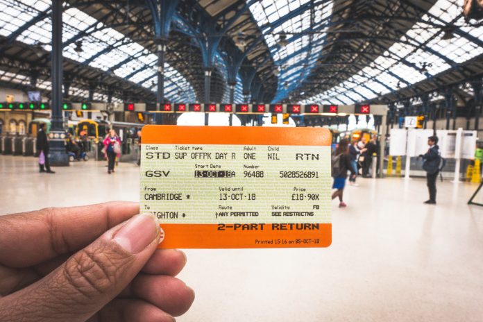 hand holding a train ticket in a station in the UK