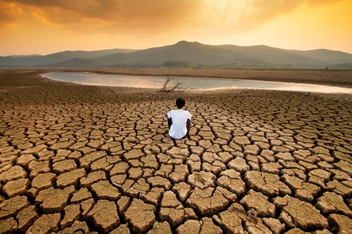 Man sitting on dry land as a result of climate change