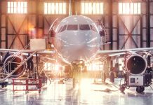 Airplane under repair in the aerospace hangar in the background of the gate and bright sunlight