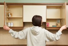 Woman looking at empty cupboards, malnourishment concept