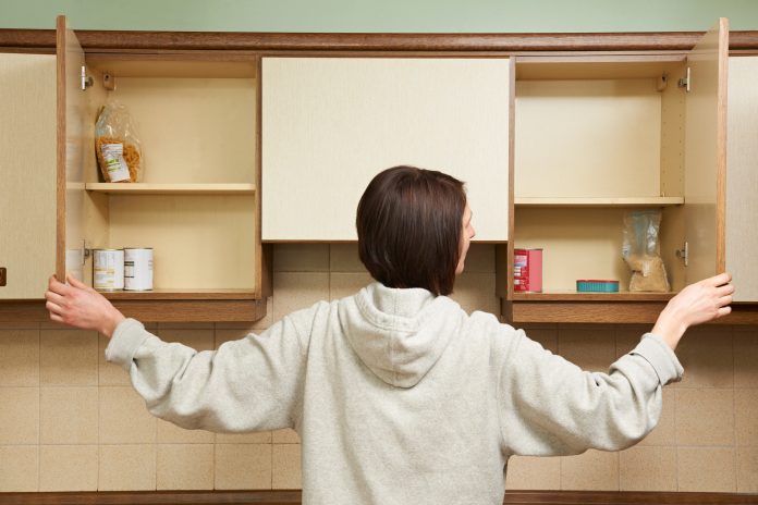 Woman looking at empty cupboards, malnourishment concept