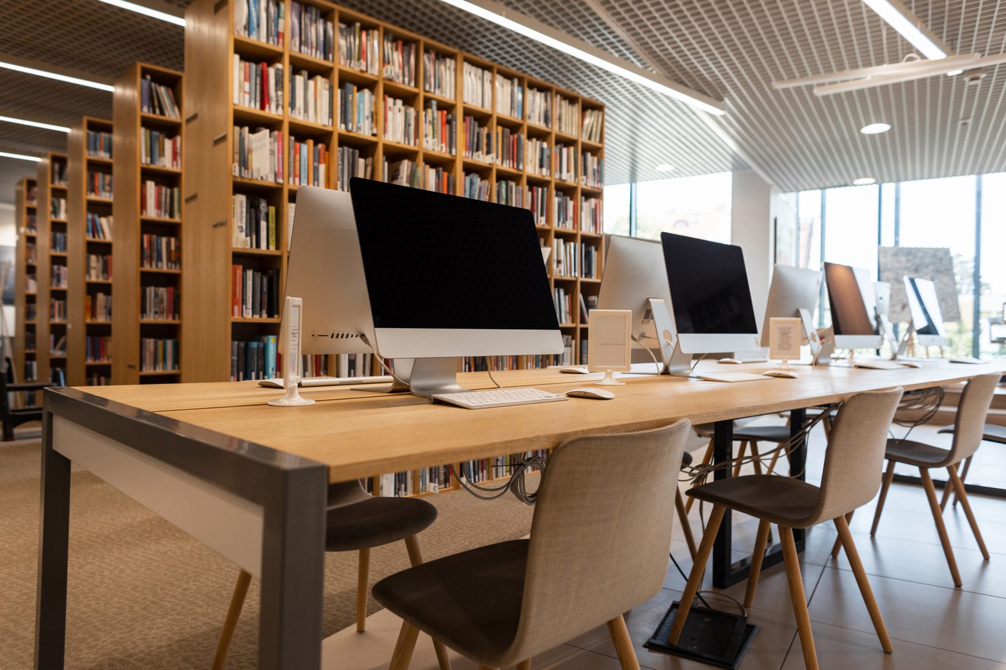 image of a library computer. a big mac desktop with bookshelves behind 