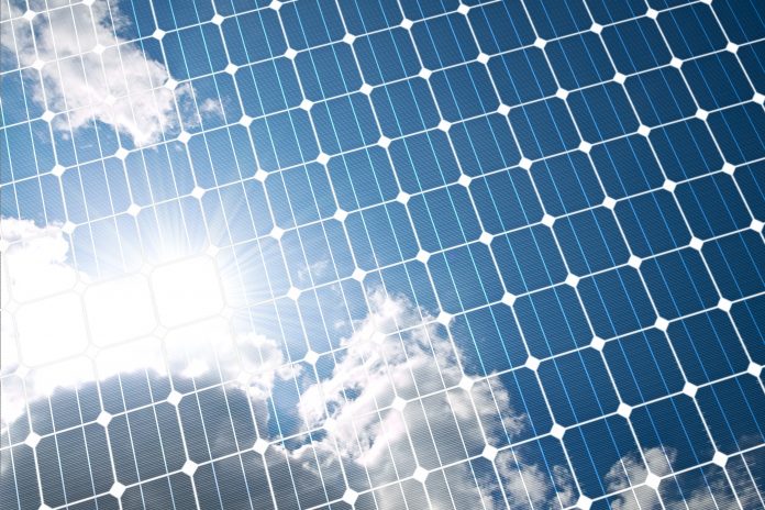 Image of a solar panel reflecting the image of some clouds on a sunny day