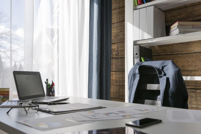 Empty office with suit jacket hung over back of chair