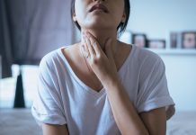 Woman holding her throat due to sore throat pain