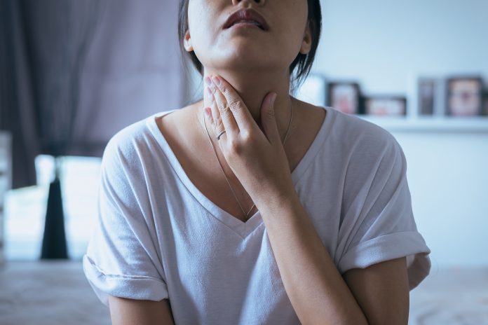 Woman holding her throat due to sore throat pain