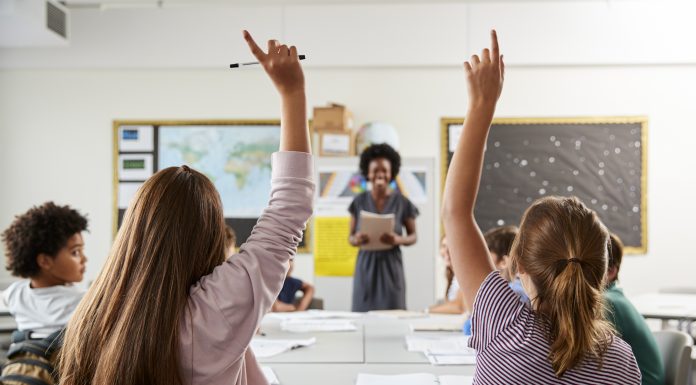 teacher shortages, picture of a teacher in a high school classroom, student asking questions