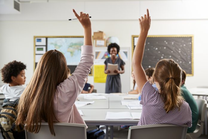 teacher shortages, picture of a teacher in a high school classroom, student asking questions