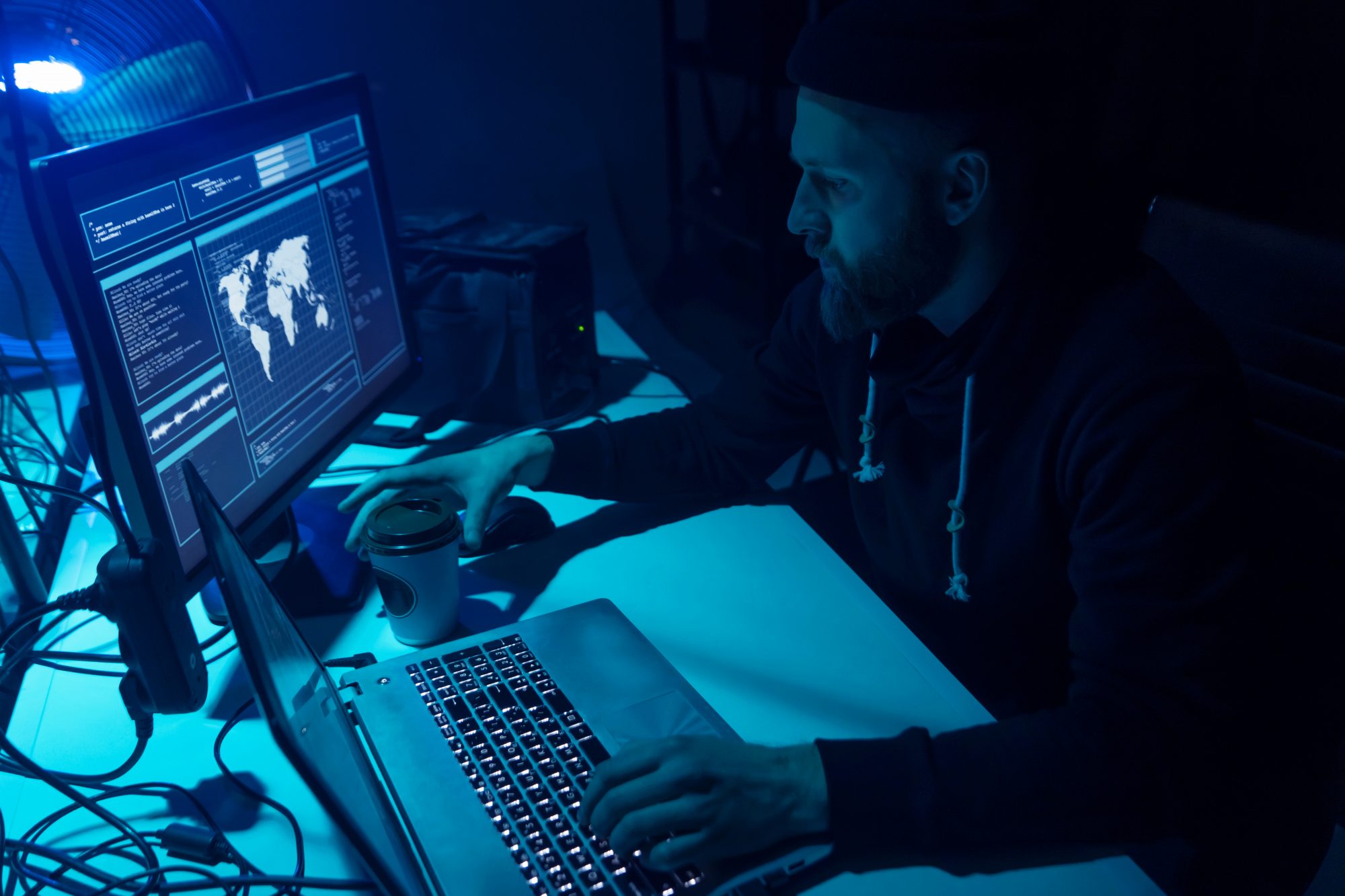 Ransomware hacker working on computer in dark room
