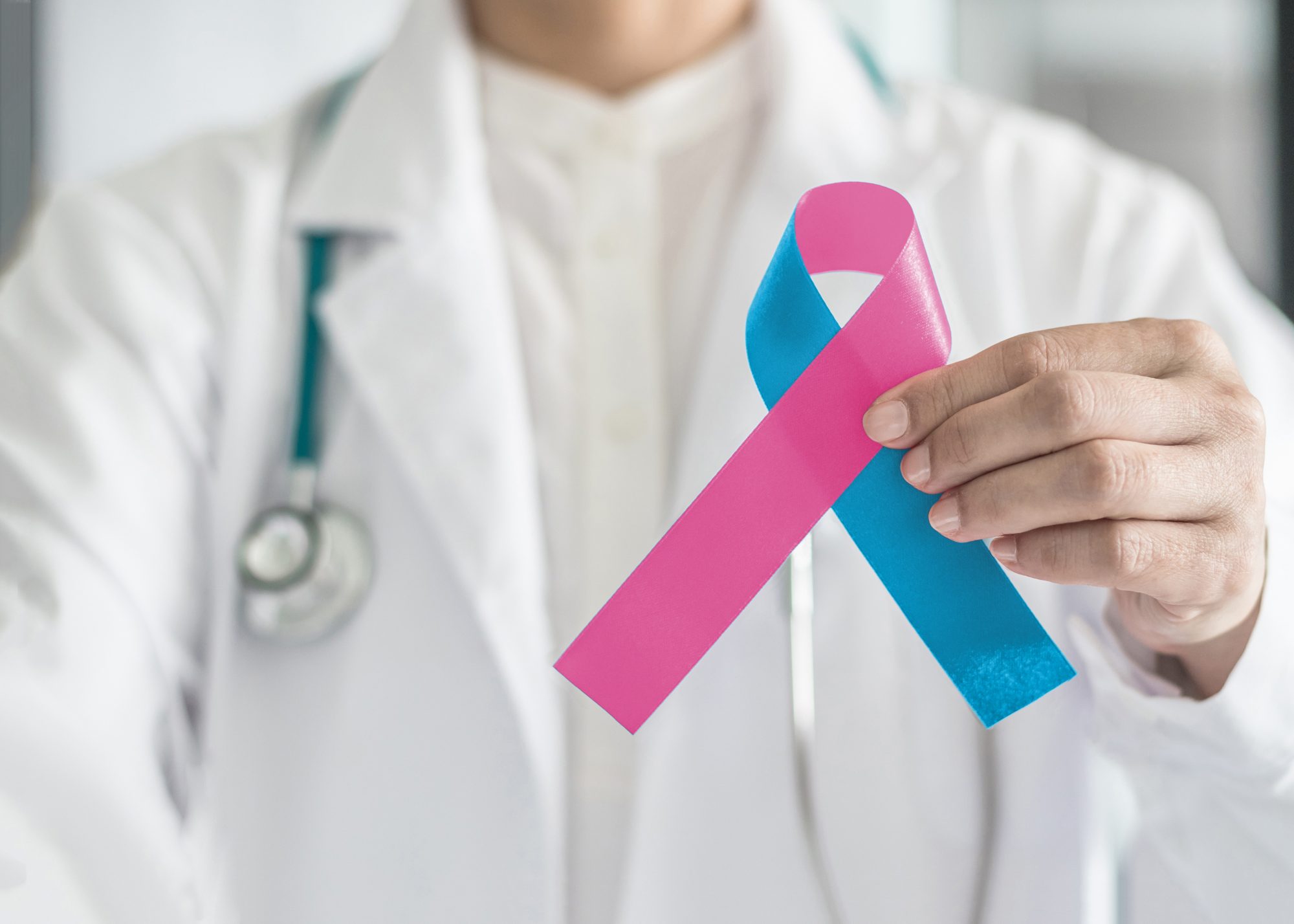 Doctor holding pink and blue ribbon to show respect for babies born with birth defects and/or babies who are born with Sudden Infant Death Syndrome