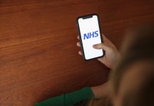 someone holding a phone looking at the NHS app: NHS digital