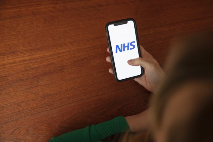 someone holding a phone looking at the NHS app: NHS digital