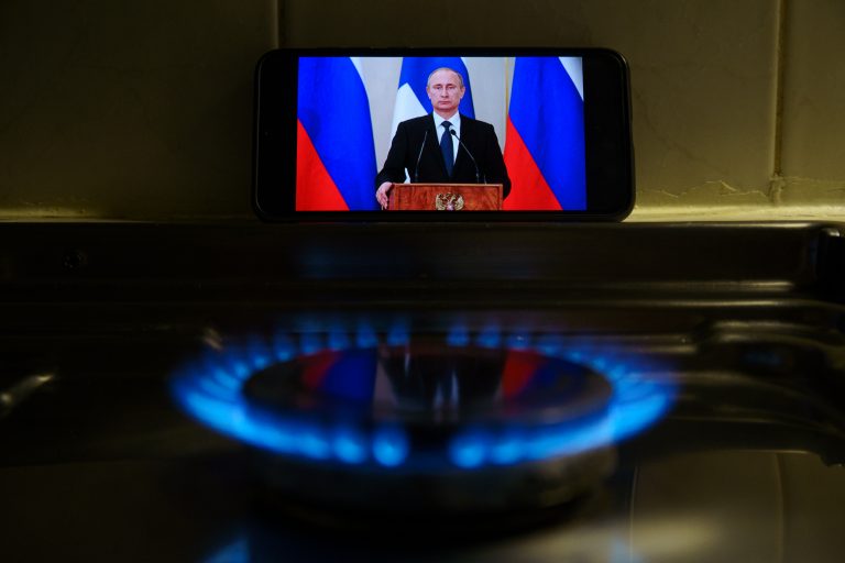 Phone showing Putin on screen propped up by gas stove