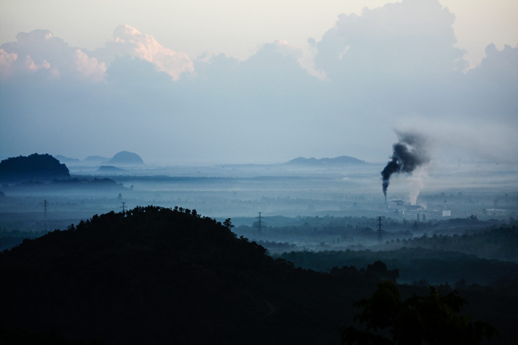 Picture of a landcape with carbon emmisions coming out of a far off chimney - Carbon pricing