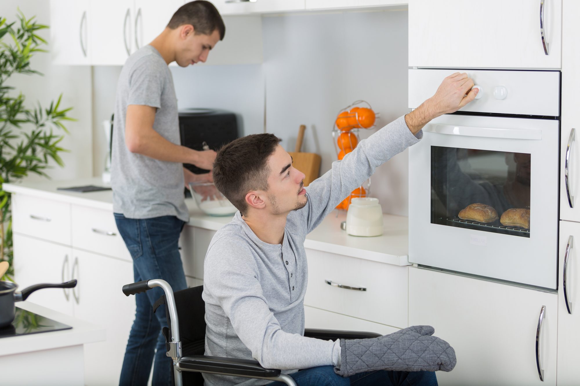 Disabled man and friend preparing meal in kitchen