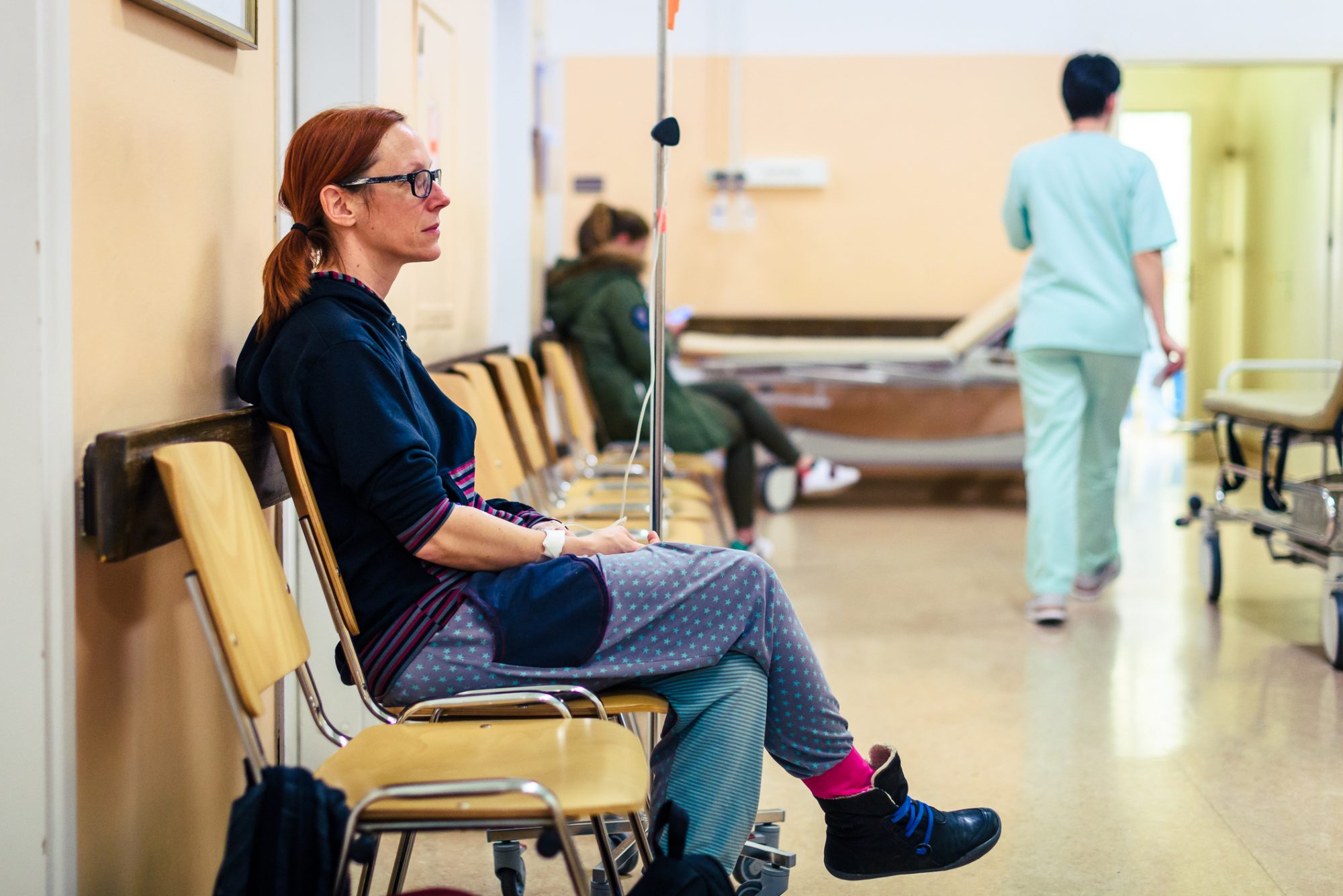 Patient sitting in hospital ward hallway waiting room with iv