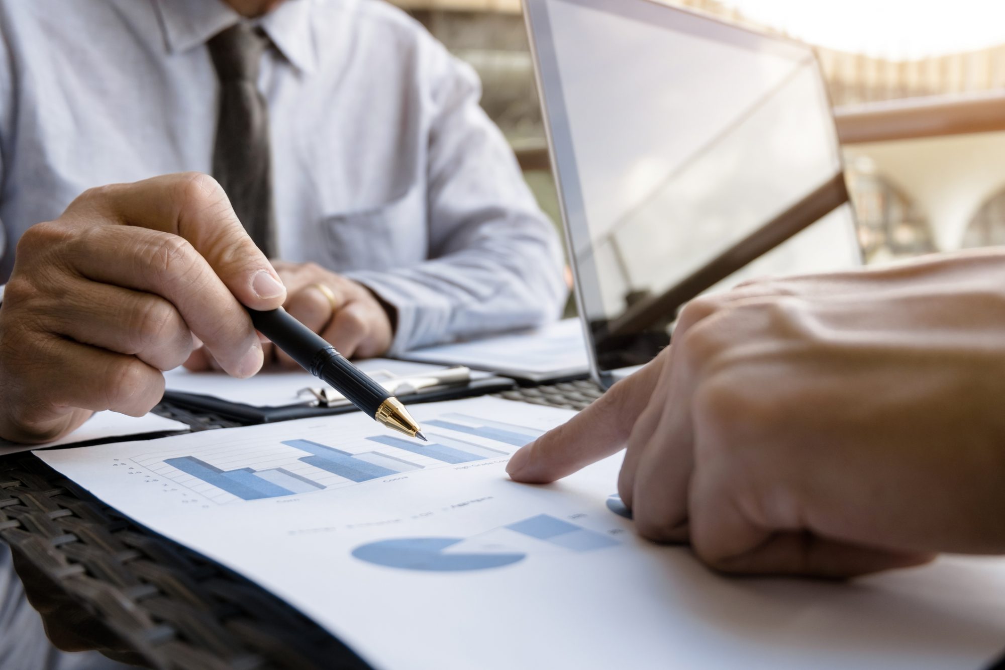 Business Executives meeting with data of sales performance at a modern outdoor workplace.