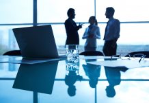 Business people talking in an office room over a laptop with data