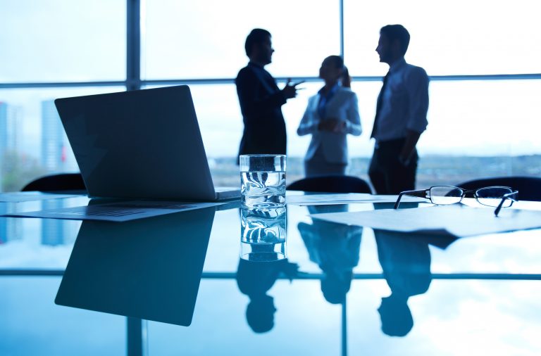 Business people talking in an office room over a laptop with data