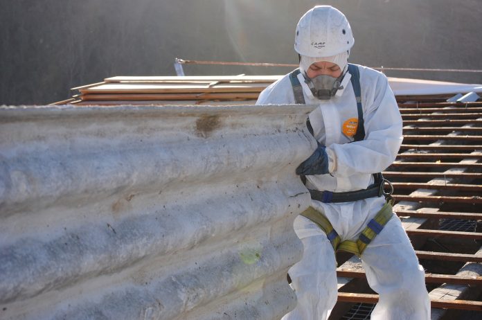 Professional worker removing asbestos roof