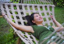 Young Asian woman relaxes on hammock in garden