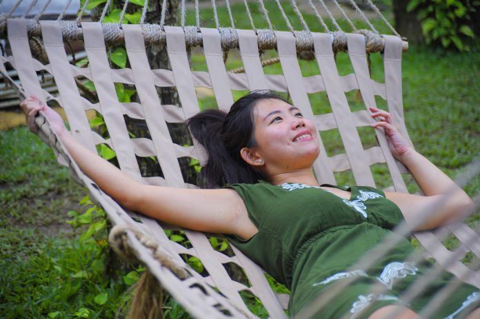 Young Asian woman relaxes on hammock in garden