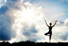 Woman standing in tree yoga pose against a beautiful sky