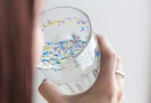 Person drinking cup of water with microplastics in