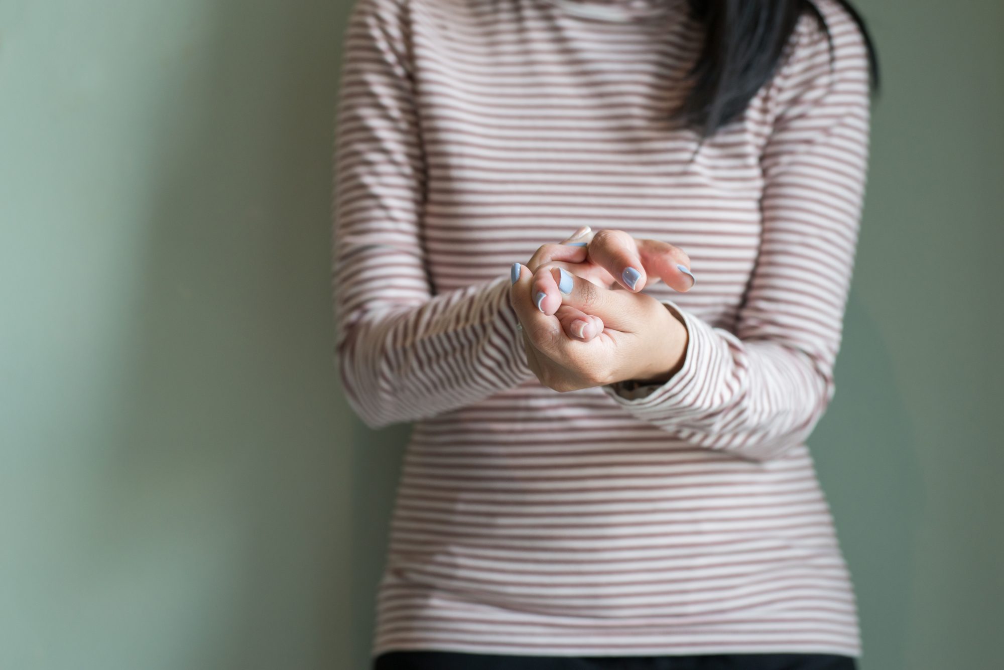 Woman in stripy jumper suffering from chronic inflammation in hands which low vitamin D levels can contribute to