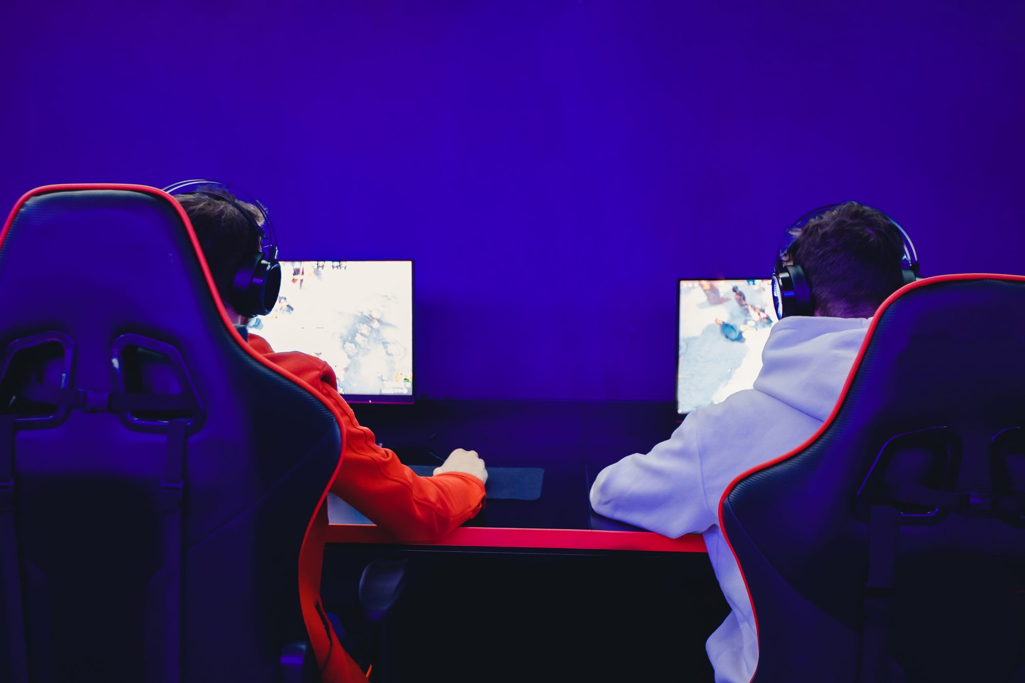Les jeunes amis jouent à des jeux vidéo en ligne avec des écouteurs dans un café du club Internet.  Concept d'équipe d'esports