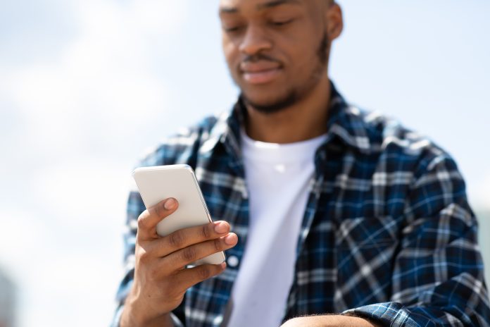Young black man looks at smartphone
