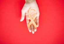 Close up of a doctor holding and showing orange awareness ribbon in her hands