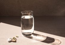 Vitamin D supplements and glass of water sitting on table in sunlight