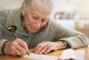 Older women leaning over table and writing a letter as a leisure activity