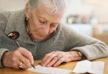 Older women leaning over table and writing a letter as a leisure activity