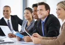 Group Of Business People Listening To Colleague Addressing Office Meeting