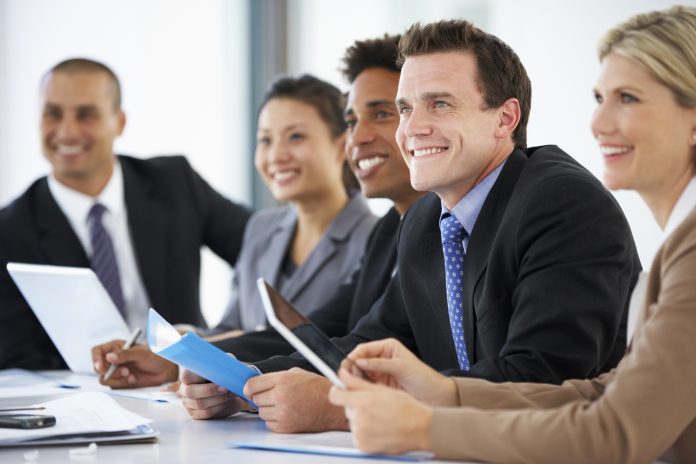 Group Of Business People Listening To Colleague Addressing Office Meeting