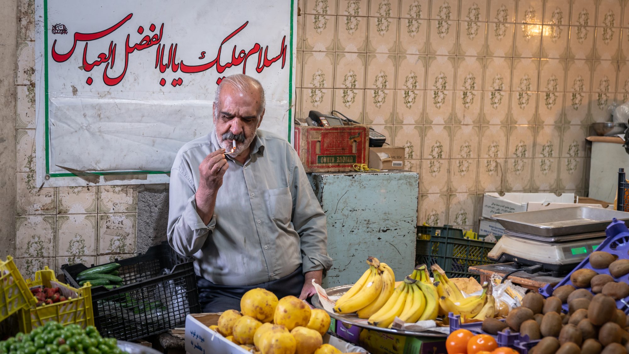 Iranian greengrocer selling fruit in his shop in Grand Bazaar of Isfahan, Iran