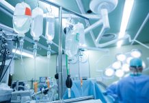 IV bags and bottles hanging on poles during a real surgery