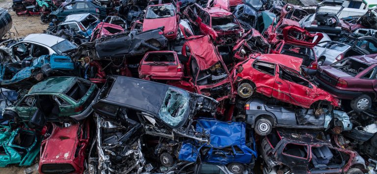 Old rusty cars piled up on top of each other in scrapyard