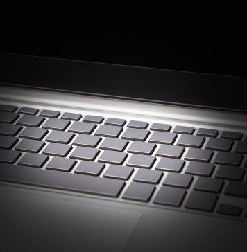 Keyboard of laptop lit up against black background