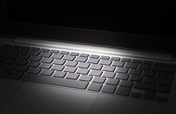 Keyboard of laptop lit up against black background