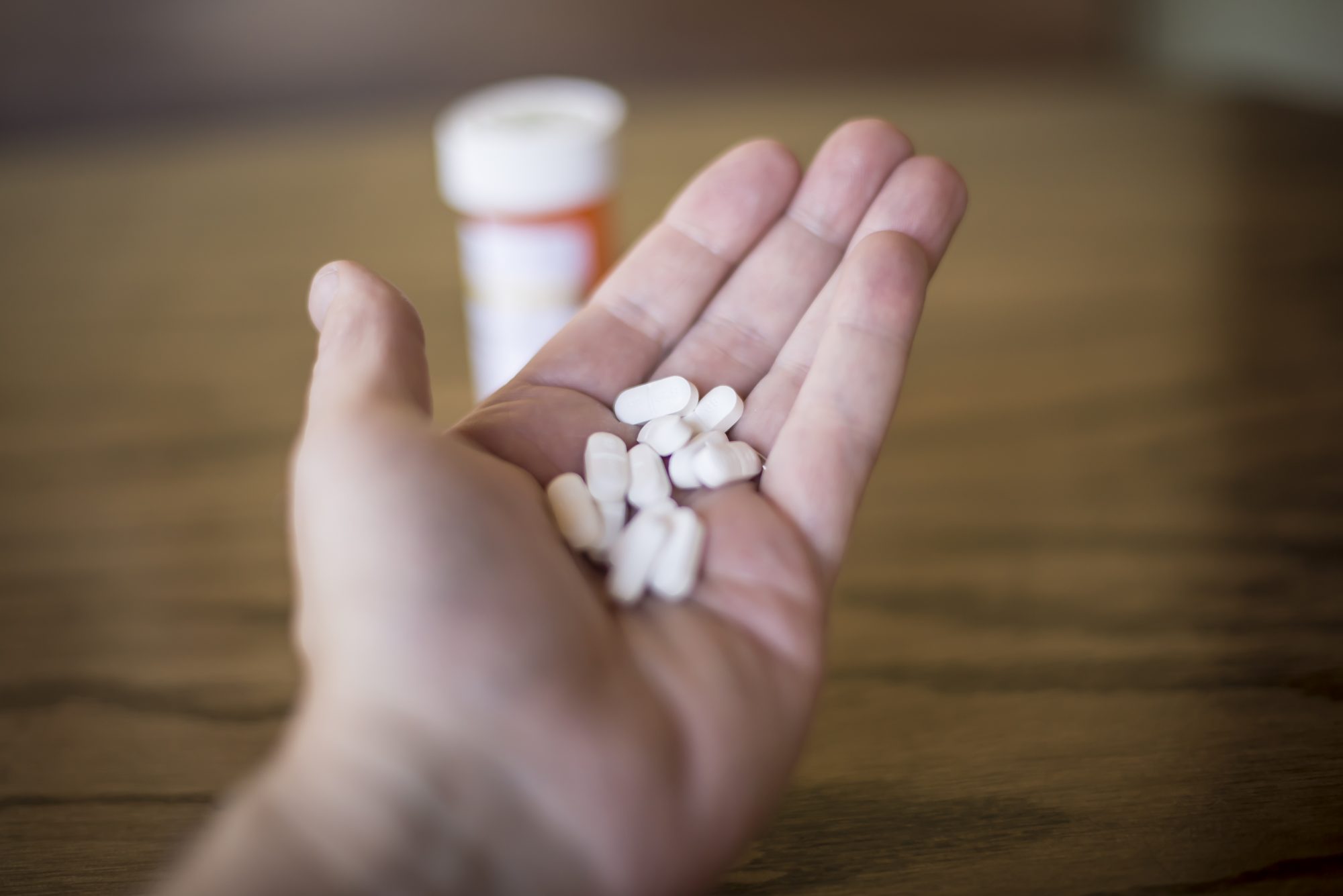 Person holding handful of white pills