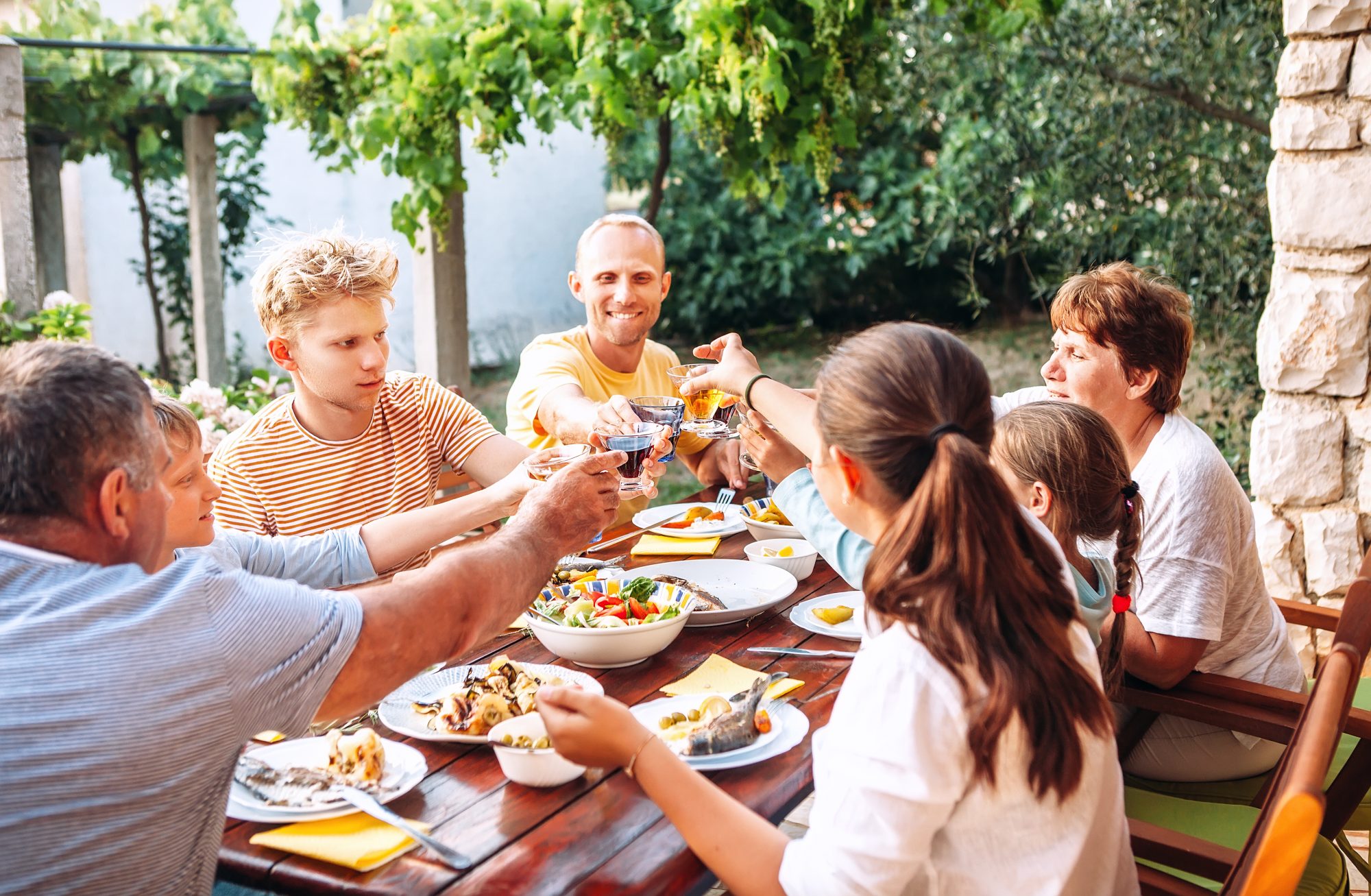 Large family sitting round a table outside eating dinner