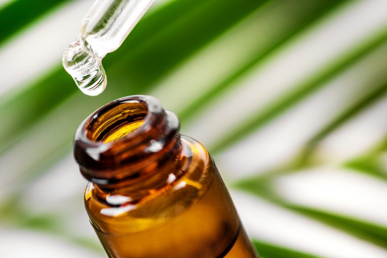 Bottle of CBD and pipette against a green and white background