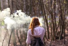 Young school girl vaping in wooded area